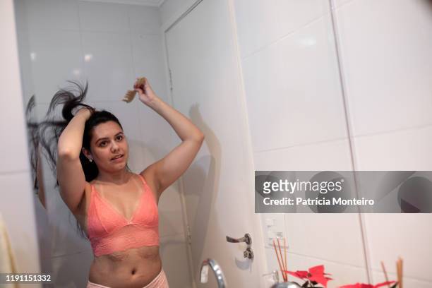 mulher penteando seu cabelo em frente ao espelho, vestindo lingerie - penteando stockfoto's en -beelden