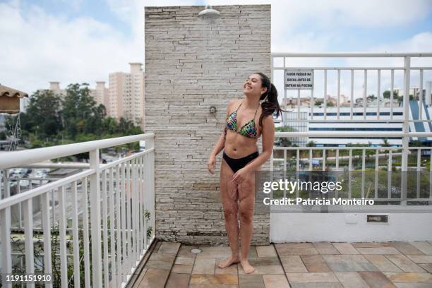 mulher toma ducha antes de entrar na piscina, com suas cicatrizes à mostra - ducha stock-fotos und bilder