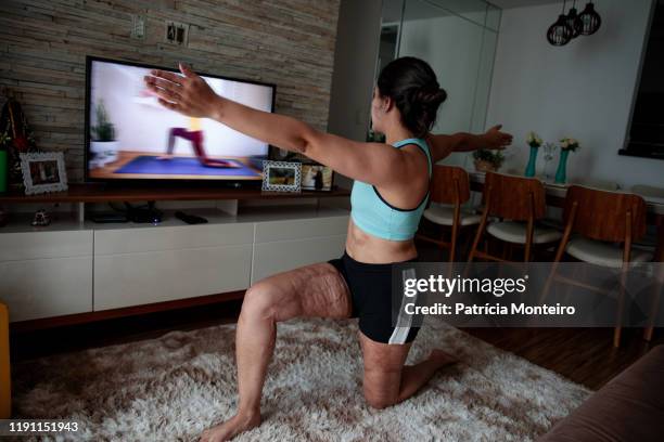 mulher praticando ioga na sala de sua casa, com suas cicatrizes à mostra - praticando stock pictures, royalty-free photos & images