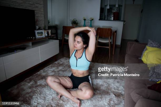 mulher praticando ioga na sala de sua casa, com suas cicatrizes à mostra - praticando bildbanksfoton och bilder