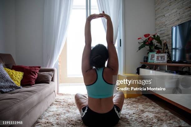 mulher praticando ioga na sala de sua casa, com suas cicatrizes à mostra - praticando stockfoto's en -beelden