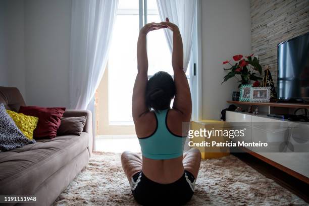 mulher praticando ioga na sala de sua casa, com suas cicatrizes à mostra - praticando stock pictures, royalty-free photos & images