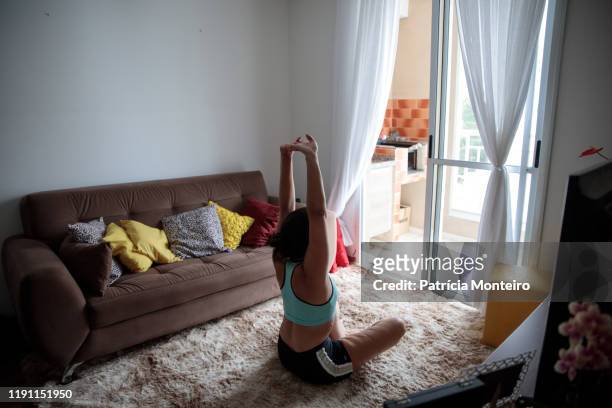 mulher praticando ioga na sala de sua casa, com suas cicatrizes à mostra - praticando stockfoto's en -beelden
