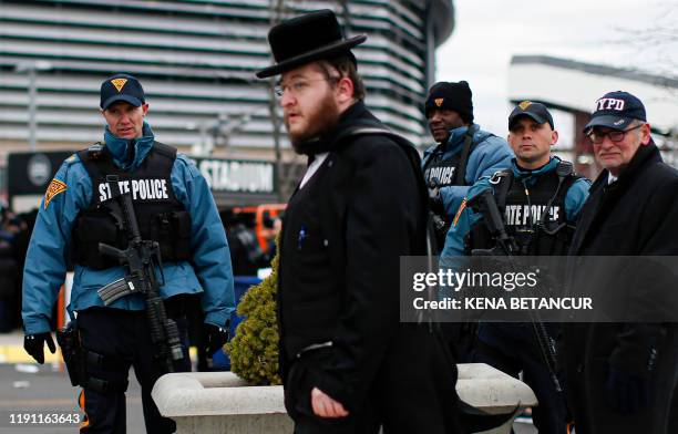 New Jersey State Police officers stand guard as people congregate at the MetLife Stadium to celebrate Siyum HaShas, the completion of the reading of...