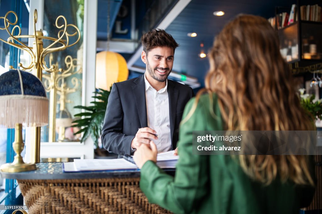 Hotel receptionist helpt gasten om in te checken