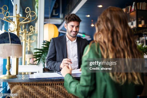 hotel receptionist assisting guest for checking in - receptionist stock pictures, royalty-free photos & images