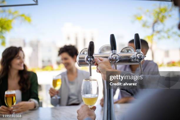 barman vullen bierglas bij bar teller - beer tap stockfoto's en -beelden