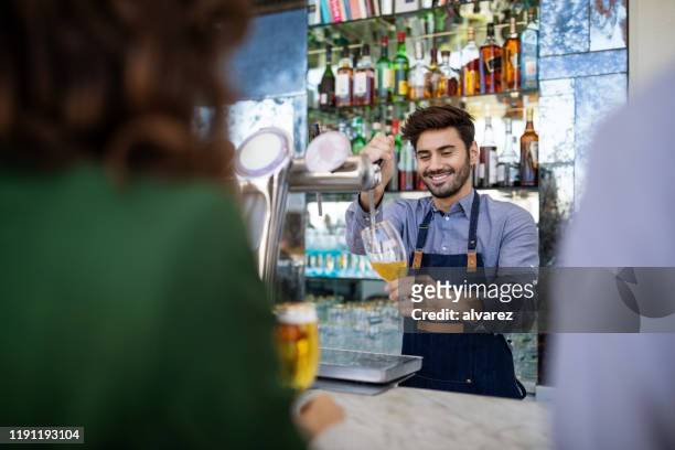 bartender serviert bier eisern an die kunden - bier zapfhahn stock-fotos und bilder