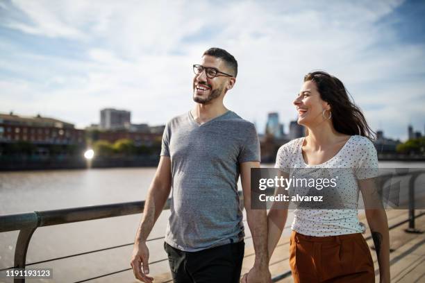 feliz pareja joven caminando juntos en el paseo marítimo de la ciudad - bulevar fotografías e imágenes de stock