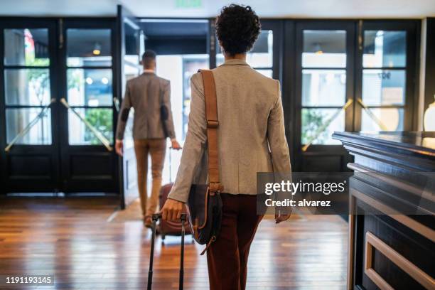 business people with luggage leaving the hotel - left imagens e fotografias de stock