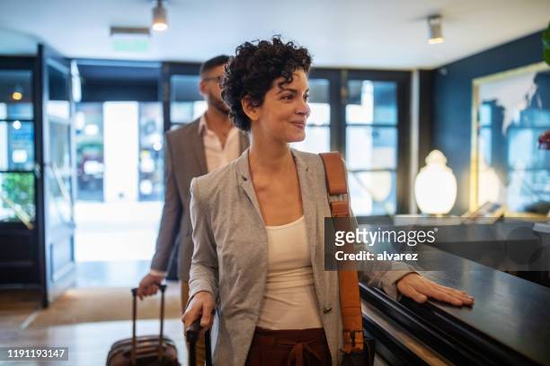 business travelers arriving at hotel reception desk - hotel stock pictures, royalty-free photos & images