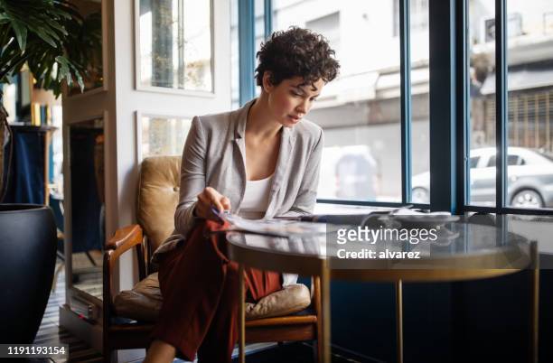 mujer leyendo una revista en el café - revista fotografías e imágenes de stock