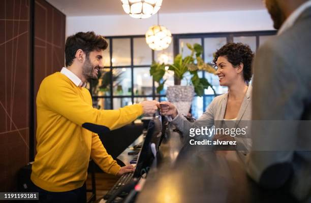 business woman getting key card from hotel reception - debit cards credit cards accepted stock pictures, royalty-free photos & images