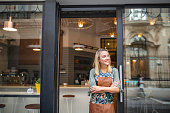 Young Cafe Owner Standing with Arms Crossed at Front Door