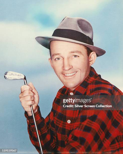 Bing Crosby , US actor and singer, wearing a grey fedora, with a black band, and a red-and-black check shirt, and holding a golf club, engraved 'Bing...