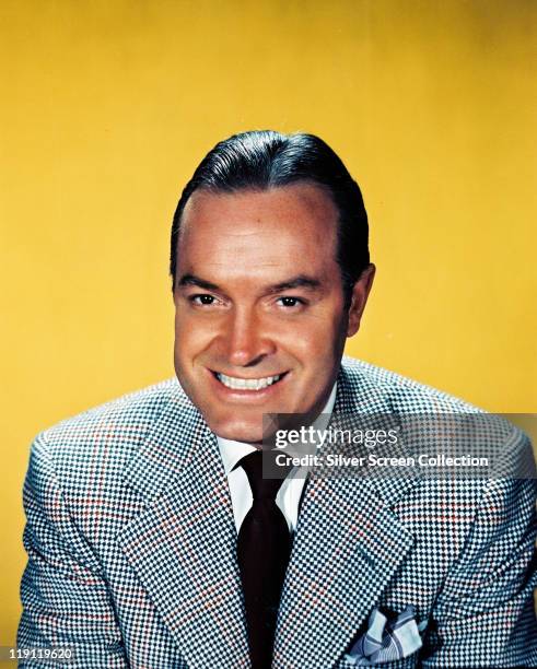 Bob Hope , British actor and comedian, smiling in a studio portrait, against a yellow background, circa 1950.