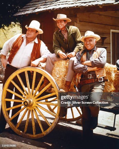 Dan Blocker , Michael Landon and Lorne Greene posing beside a cart laden with hay bales in a publicity still issued for the US television series,...