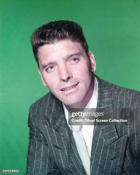 Headshot of Burt Lancaster , US actor, wearing a pin-striped jacket and white shirt in a studio portrait, against a green background, circa 1950.