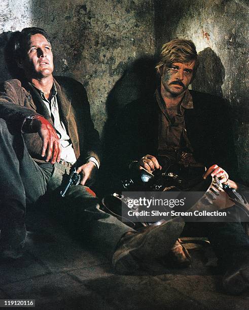 Paul Newman , holding a handgun with his other hand covered in blood, sitting alongside a despairing Robert Redford in a publicity still issued for...