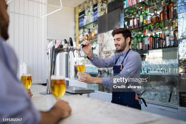 bartender feilen bier in einem glas aus hahn - beer pour stock-fotos und bilder