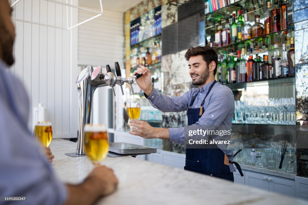 Bartender filing beer in a glass from tap