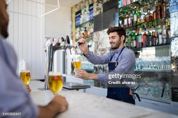 bartender filing beer in a glass from tap - serving size stock pictures, royalty-free photos & images