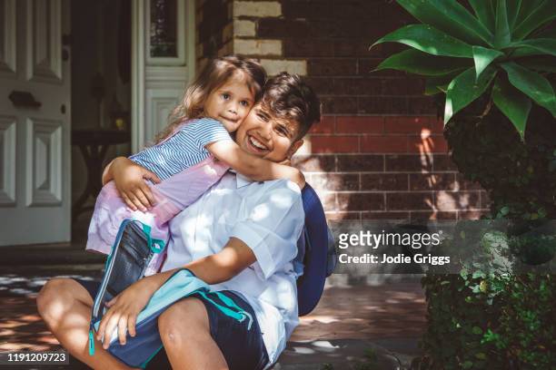 happy brother and sister embracing on the front door step of their house - thisisaustralia stock-fotos und bilder