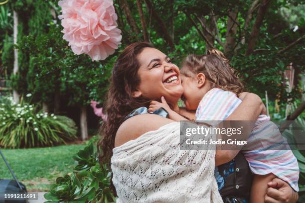 mother embracing her daughter during a family celebration in the backyard - thisisaustralia stock-fotos und bilder