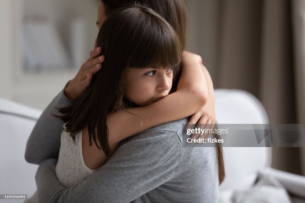 Close up view of upset little daughter cuddling mother