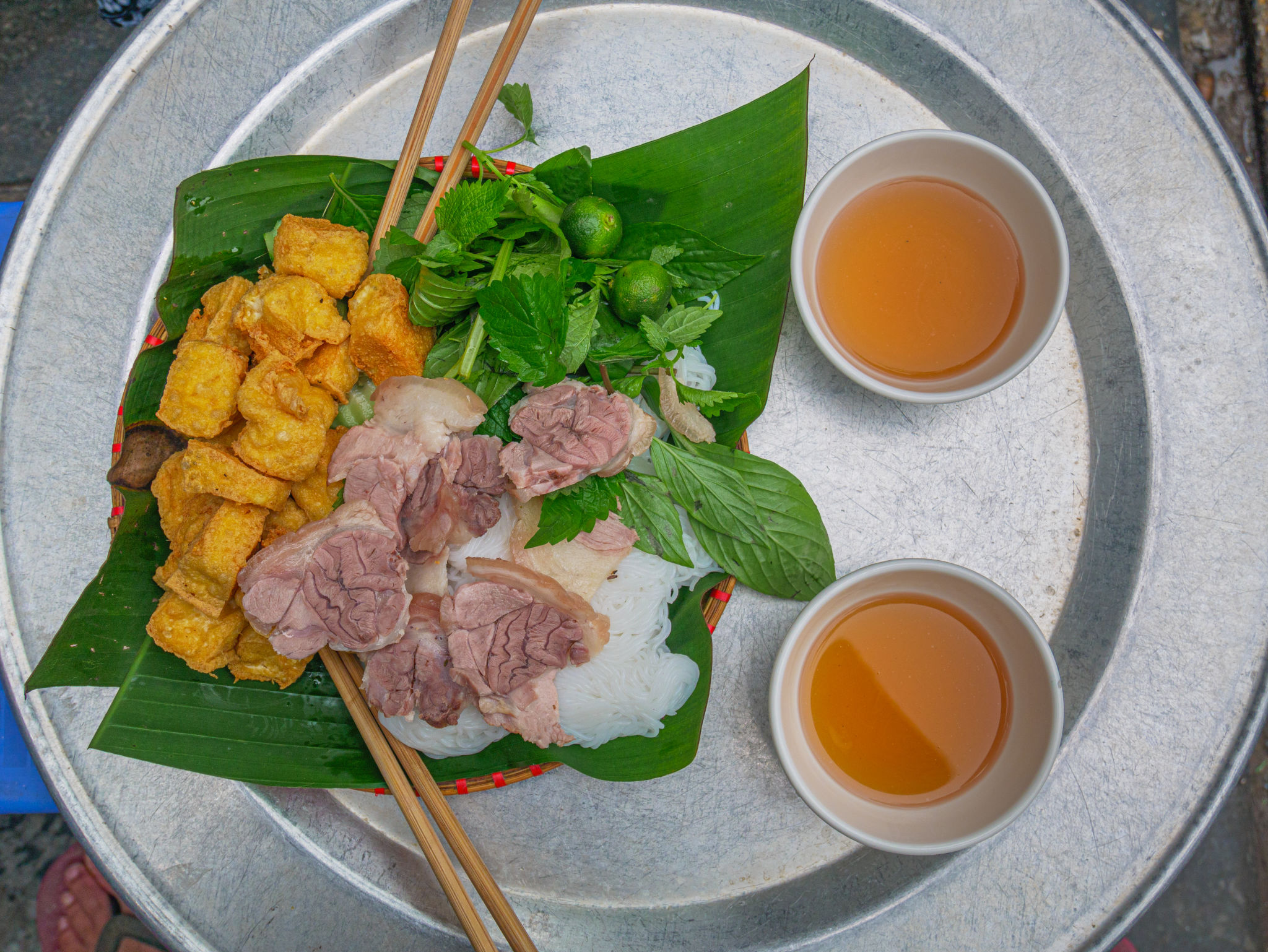 Bun Cha, traditional vietnamese dish served for lunch as street food in Hanoi. Minced pork fried tofu rice noodles herbs on banana leaf and soup. Bun Cha, traditional vietnamese dish served for lunch as street food in Hanoi. Minced pork fried tofu rice noodles herbs on banana leaf and soup.