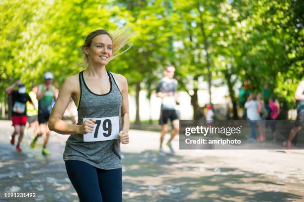 gelukkige jonge vrouw running marathon op zonnige dag in het voorjaar - marathon stockfoto's en -beelden