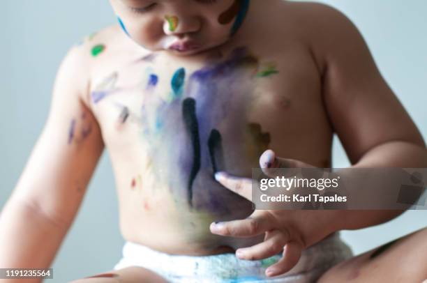 a male asian toddler is painting with watercolor - baby paint hand stock-fotos und bilder