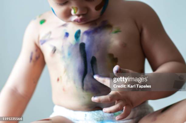 a male asian toddler is painting with watercolor - baby paint hand imagens e fotografias de stock