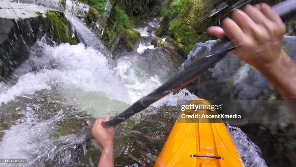 白い水のカヤッカーは滝を下るパドル