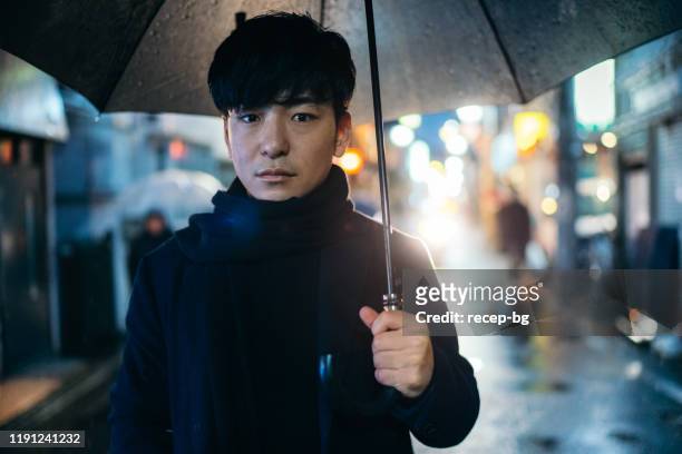 portrait of young businessman on rainy day at night - asia rain stock pictures, royalty-free photos & images