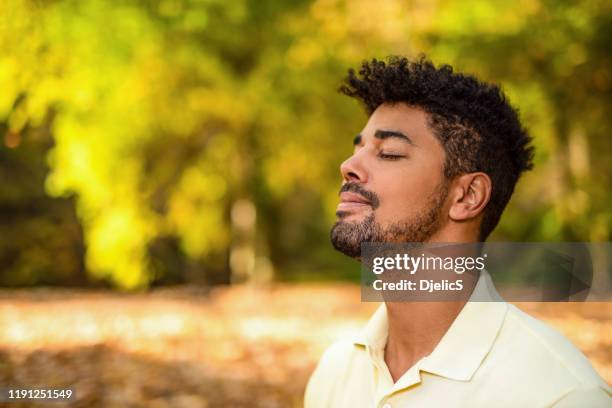 young man meditating in nature on autumn day. - meditation concentration stock pictures, royalty-free photos & images