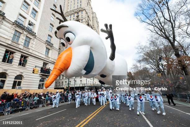 Balloon handlers fight the strong wind gusts and struggle to keep Walt Disney Animation Studios Olaf from Disney's Frozen Balloon and his nose from...