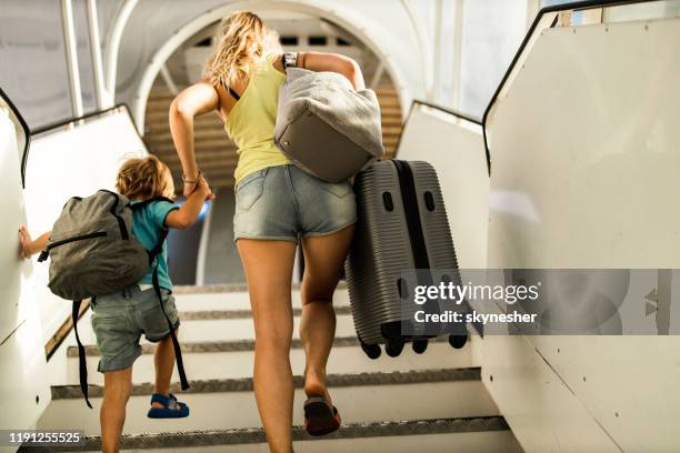 rear view of mother and son boarding in airplane. - airport stairs stock pictures, royalty-free photos & images