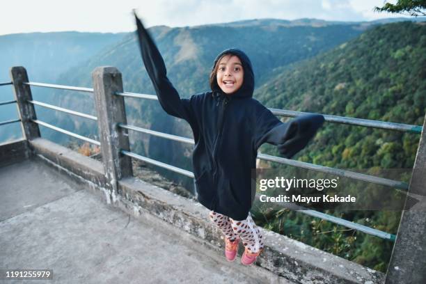 girls wearing oversized jacket jumping - valley side stock-fotos und bilder