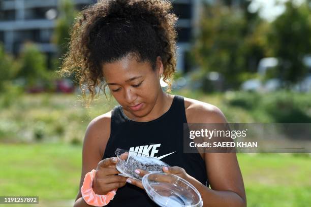 Tennis player Naomi Osaka of Japan tries a lamington cake after taking a sightseeing ride in a helicopter at the Queensland Tennis Centre in Brisbane...