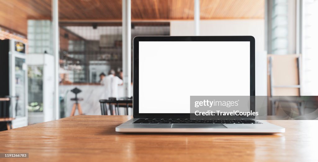 Laptop computer blank white screen on table in cafe background. Laptop with blank screen on table of coffee shop blur background.