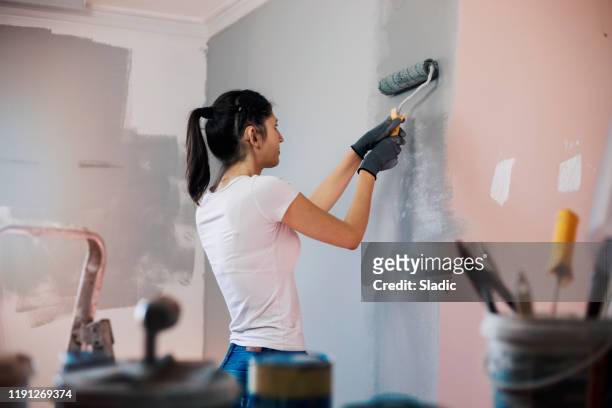 mujer joven con audífonos pintando paredes - decorar fotografías e imágenes de stock