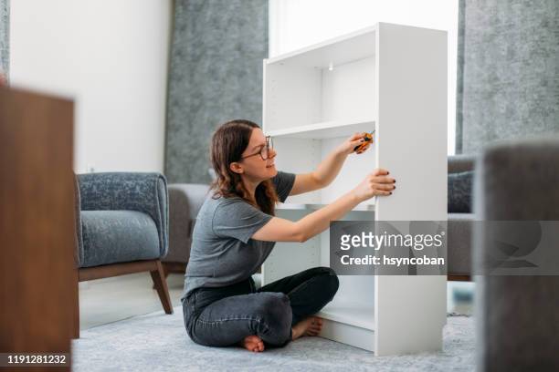 donna che assembla armadio di legno in casa - mobilio foto e immagini stock