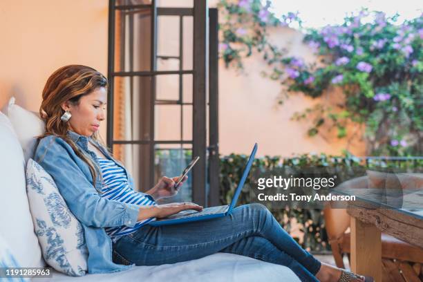 Woman using laptop and mobile phone on outdoor veranda