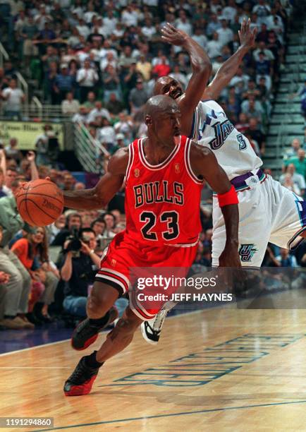 Michael Jordan of the Chicago Bulls sticks out his tongue as he goes past Bryon Russell of the Utah Jazz 11 June 1997 during game five of the 1997...