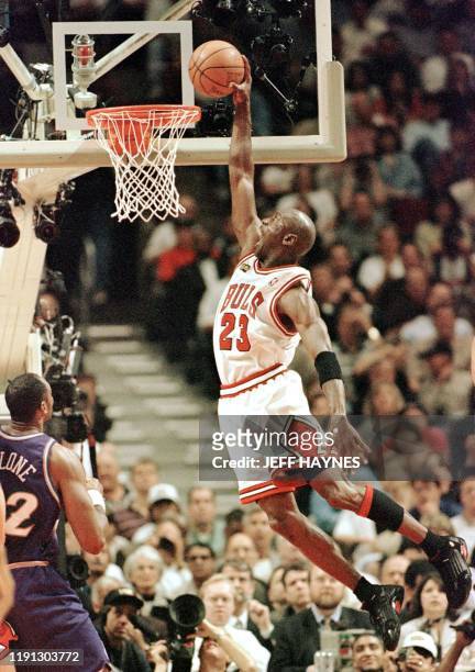 Michael Jordan of the Chicago Bulls flies in for the dunk while Karl Malone of the Utah Jazz watches 10 June during game four of the NBA Finals at...