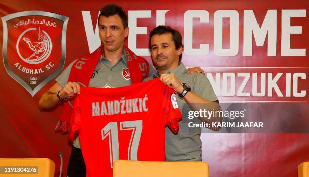 Croatian forward Mario Mandzukic is presented with the number 17 jersey by coach Rui Faria during his introduction as a new player for Qatar's Al...