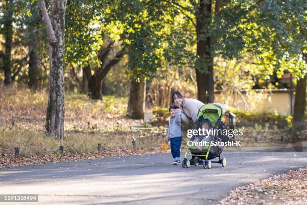 lycklig familj i offentlig park på hösten - baby pram in the park bildbanksfoton och bilder