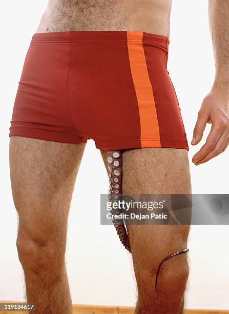 midsection of a man with an octopus tentacle coming out of his shorts - tentacle stockfoto's en -beelden