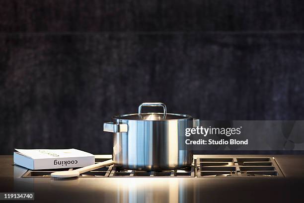 saucepan, cookery book and wooden spoon on hob. - pan stock pictures, royalty-free photos & images